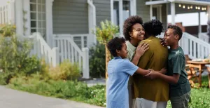 A smiling family sharing a warm hug outside their home